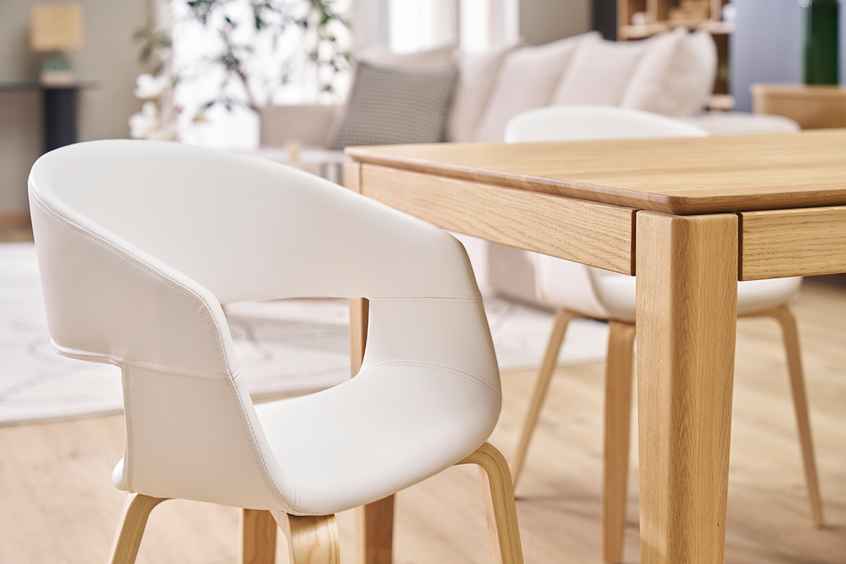Chaises design blanches et bois clair autour d'une table en bois.