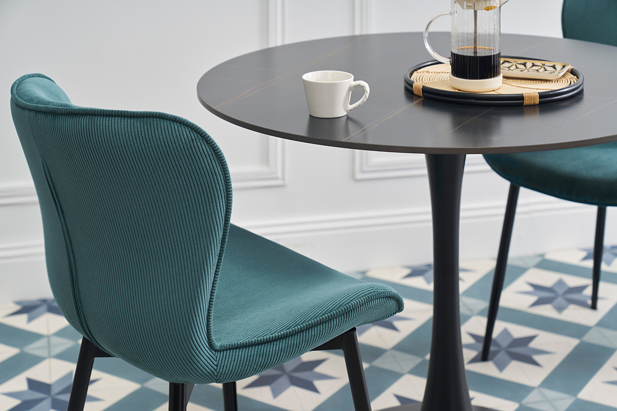 Chaise design en velours ctel bleu canard  ct d'une table noire.