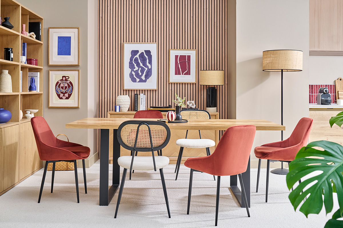 Salle  manger avec chaises velours rouge et mtal noir autour d'une table en bois.