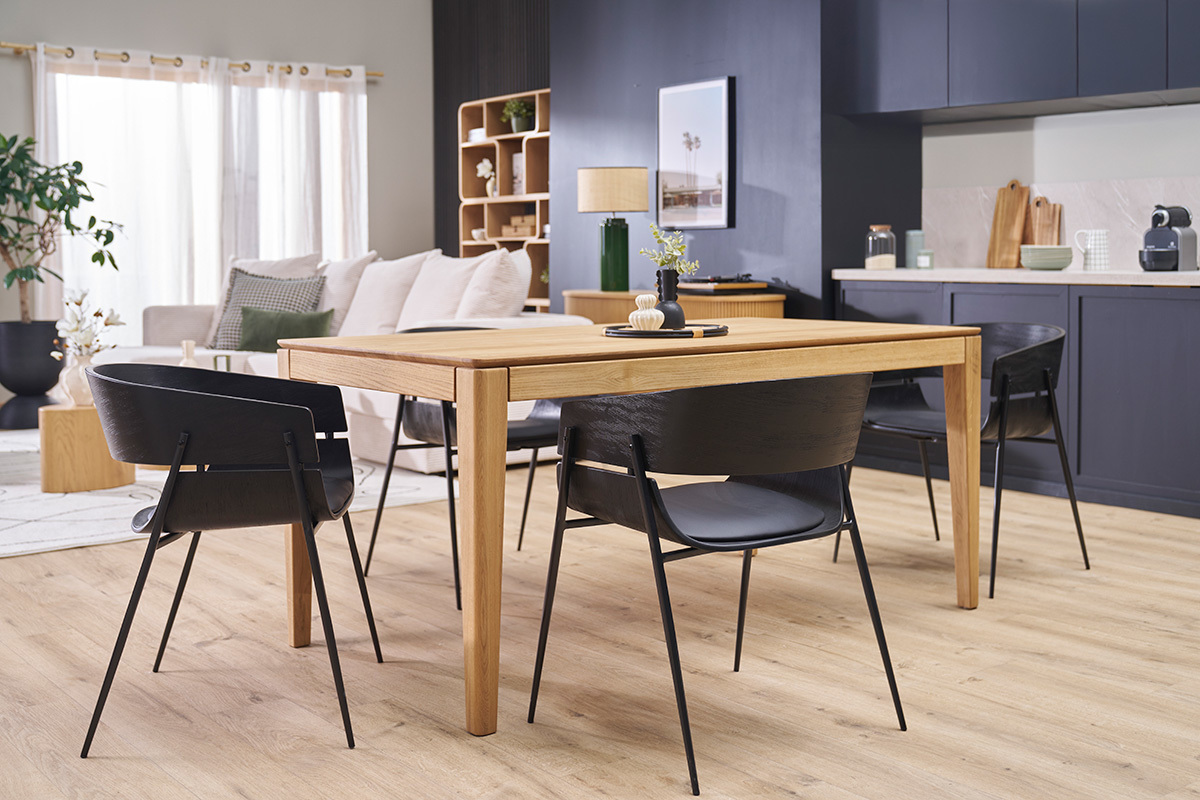 Chaises design noires WESS autour d'une table en bois dans un salon moderne.