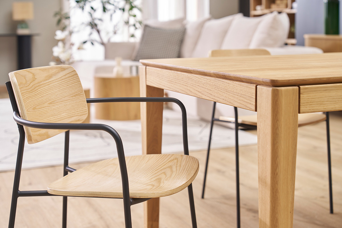 Chaises susan en bois clair avec pitement en mtal noir  ct d'une table en bois.