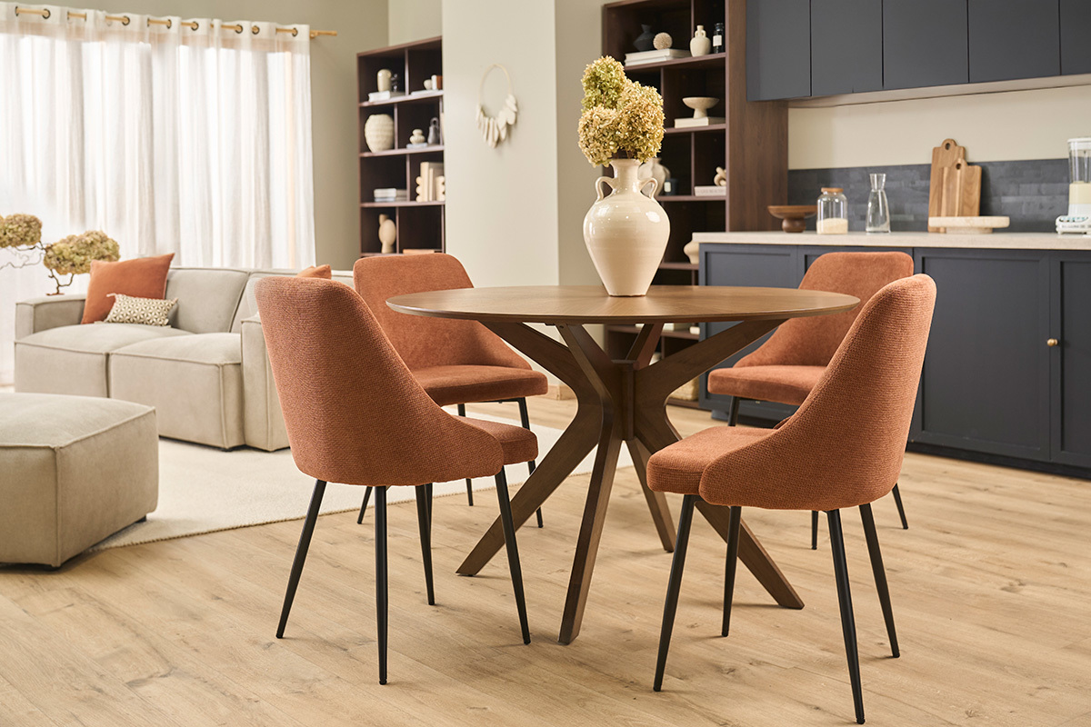 Chaises en tissu terre br�l�e avec pieds en m�tal noir autour d'une table ronde en bois dans un salon moderne.