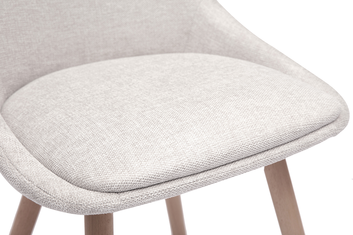 Gros plan sur l'assise rembourre d'une chaise en tissu effet velours beige et pieds en bois clair.