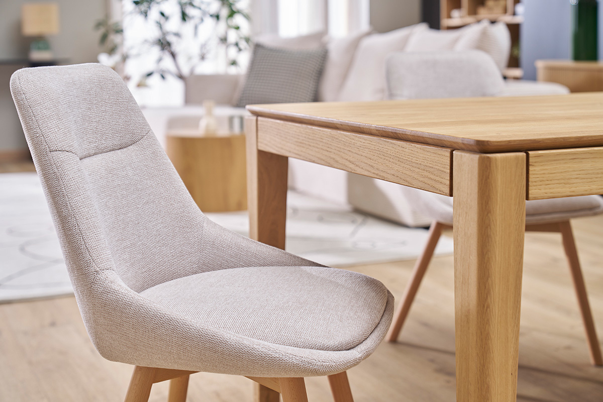 Chaise en tissu effet velours beige et bois clair  ct d'une table en bois.