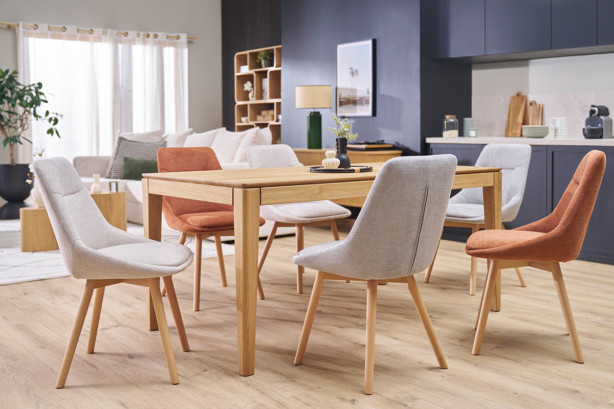 Chaises en tissu et bois autour d'une table en bois clair dans une salle  manger moderne.