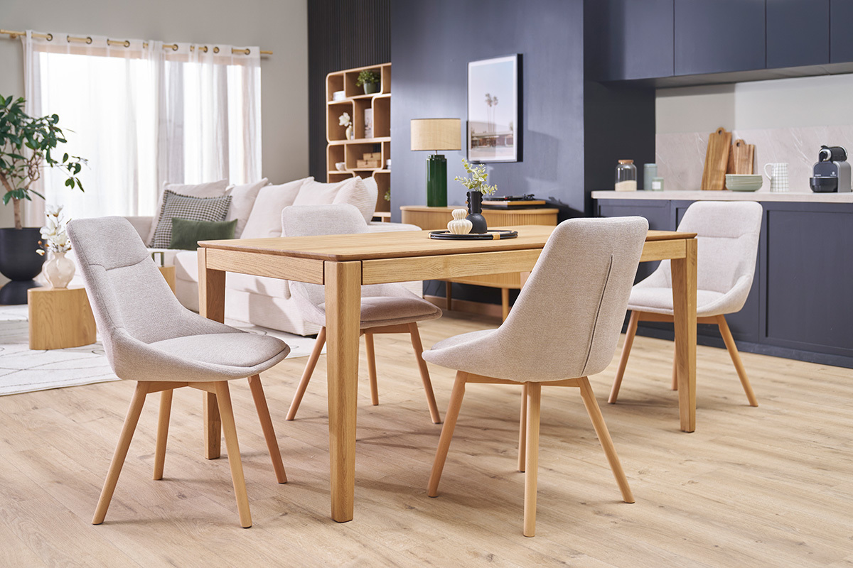 Chaises en tissu effet velours beige et bois clair autour d'une table en bois, vue d'ensemble.