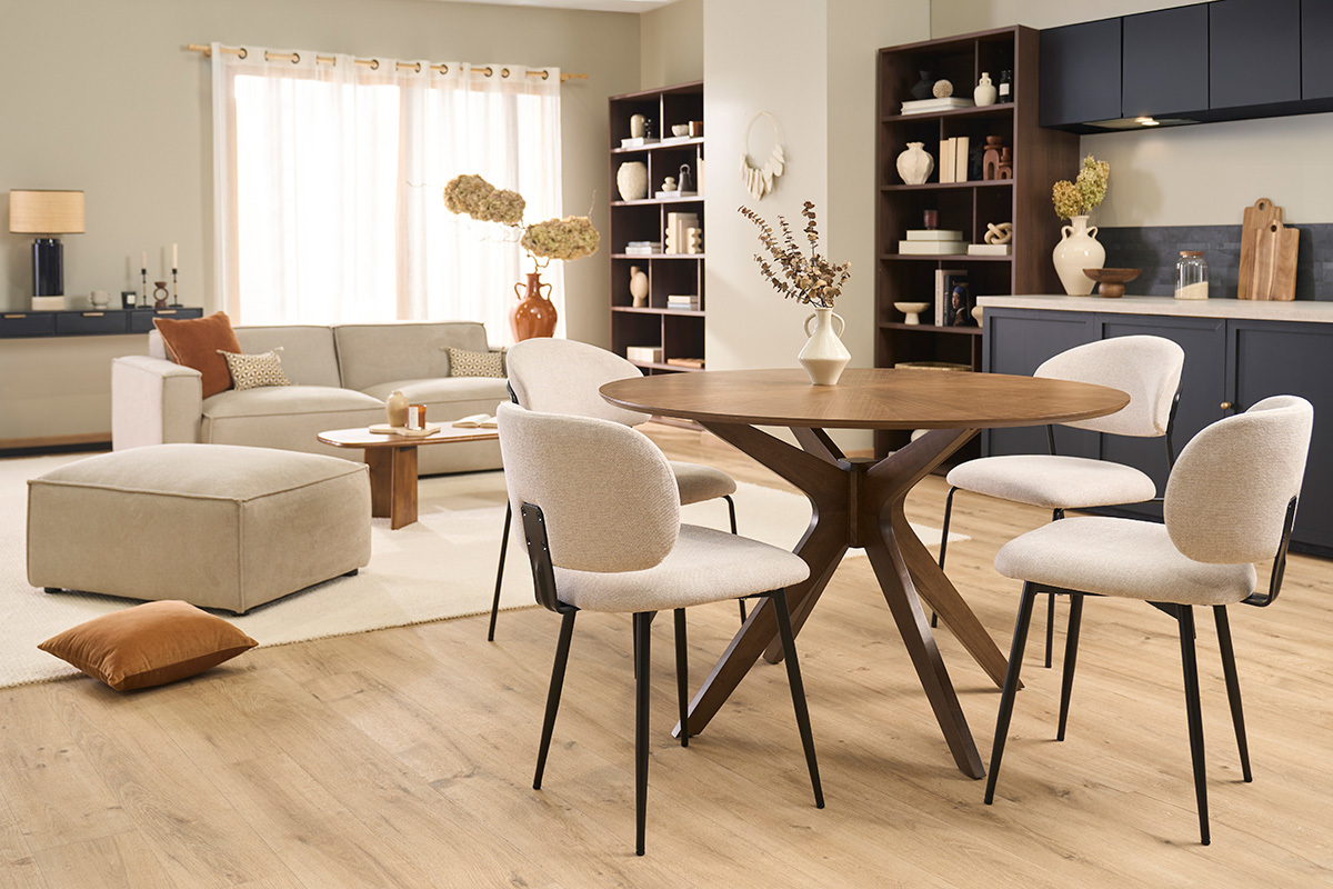 Chaises beiges en tissu effet velours et m�tal noir autour d'une table ronde en bois.