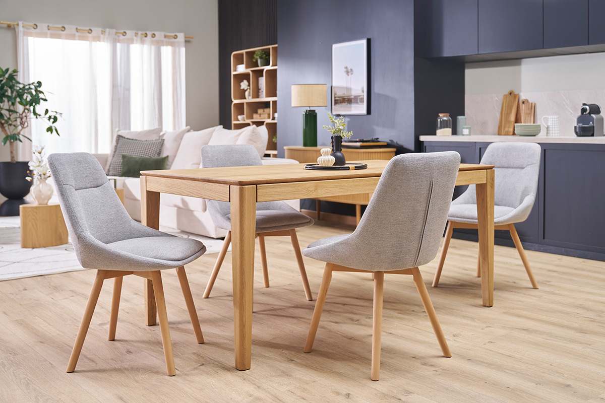 Quatre chaises ALESS gris clair autour d'une table en bois clair dans un salon moderne.