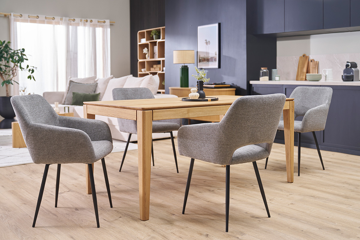 Quatre chaises LAURETTE en tissu effet velours gris et mtal noir autour d'une table en bois dans un salon.