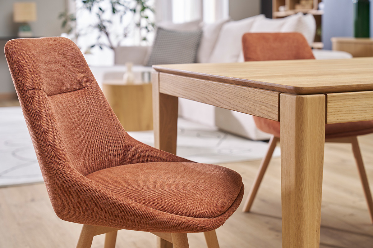 Chaises en tissu effet velours terre brle et pieds en bois clair autour d'une table.