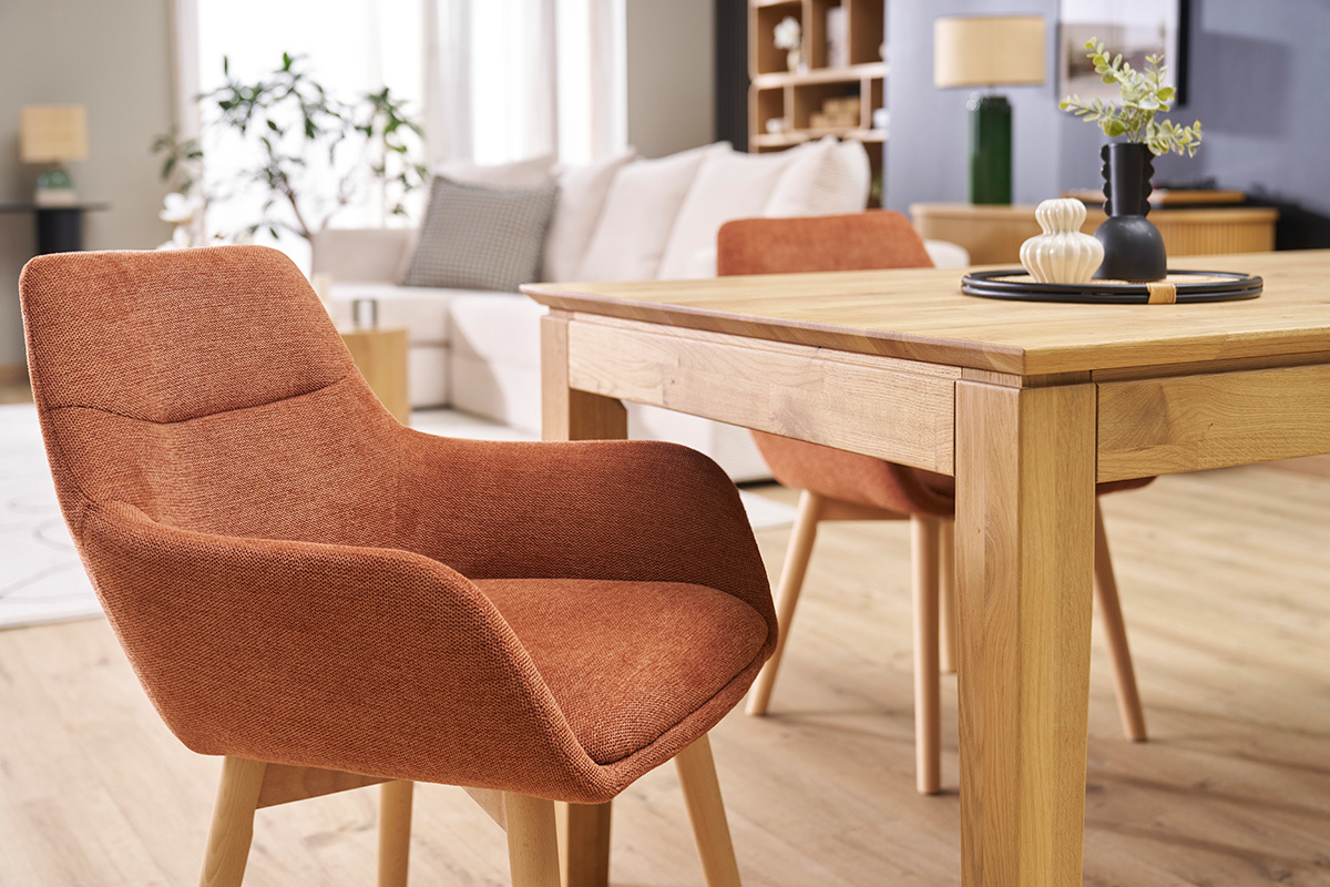 Chaises en tissu terre brle avec pieds en bois clair autour d'une table en bois dans un salon.