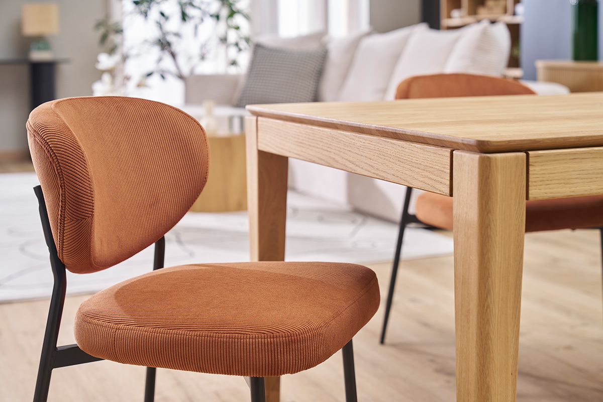 Chaises en velours ctel terre brle avec mtal noir, prs d'une table en bois clair.