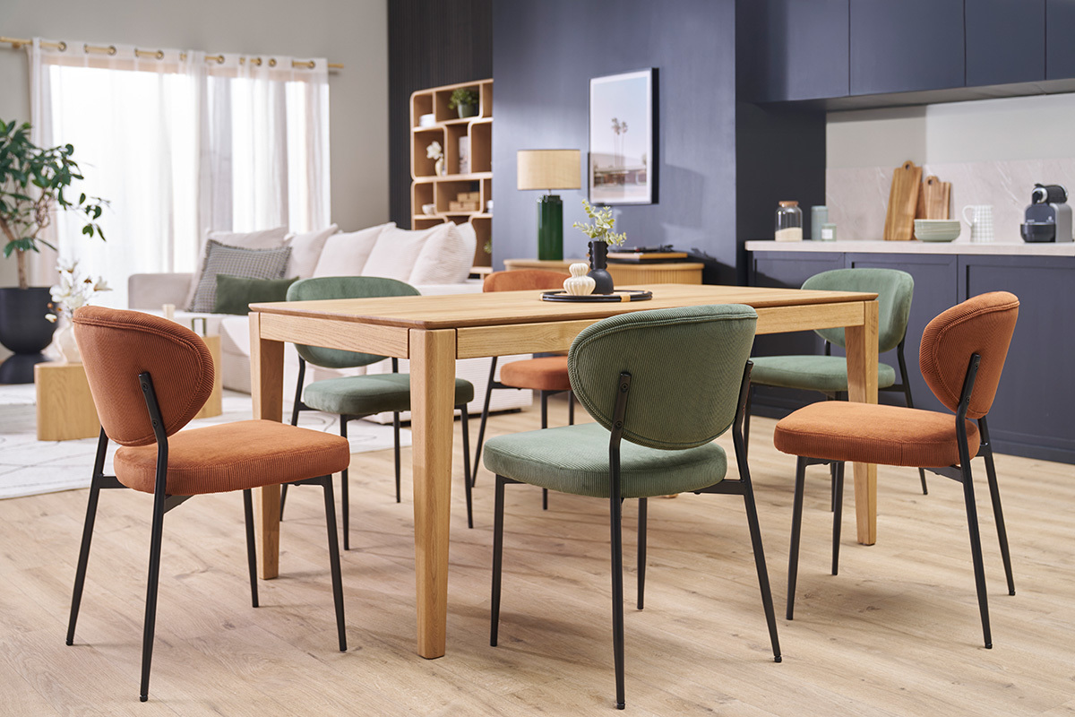 Chaises en velours ctel terre brle et mtal noir autour d'une table en bois, vue intrieure.