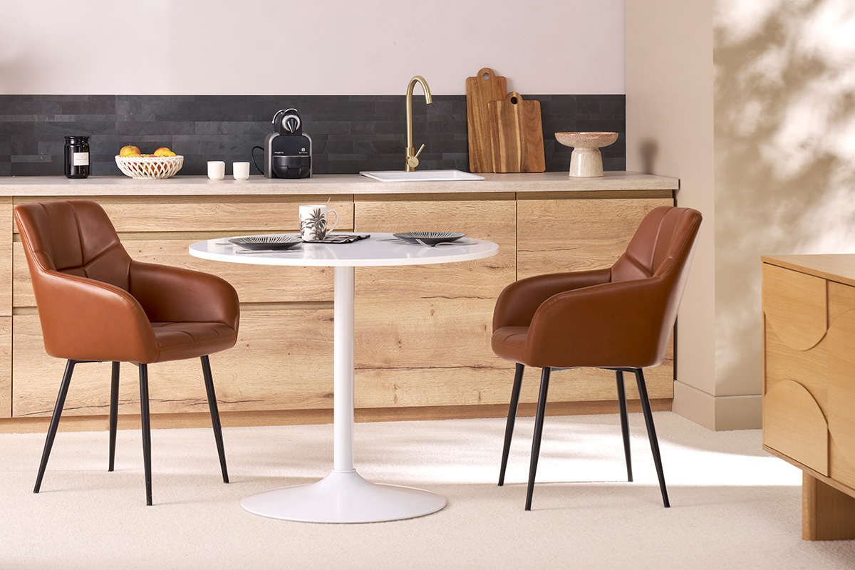 Chaises matelasses marron et mtal noir MONTERO autour d'une table blanche.