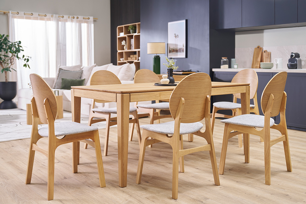 Salle  manger avec chaises scandinaves en bois clair et tissu gris autour d'une table en bois.