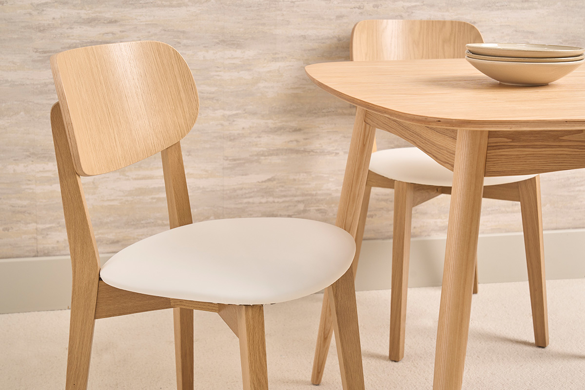 Chaises vintage en bois ch�ne clair et assise blanche, vue rapproch�e sur deux chaises autour d'une table.