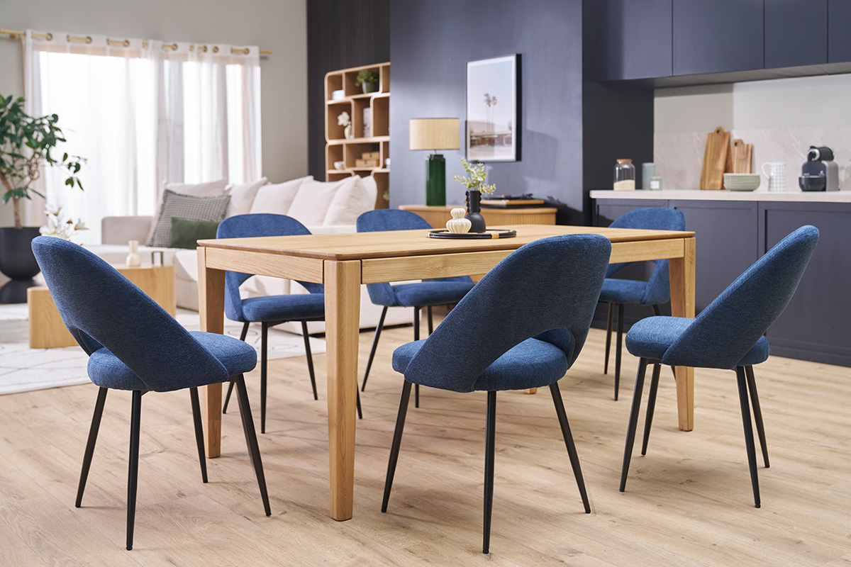 Chaises vintage bleues en tissu velours et mtal noir autour d'une table en bois dans une salle moderne.