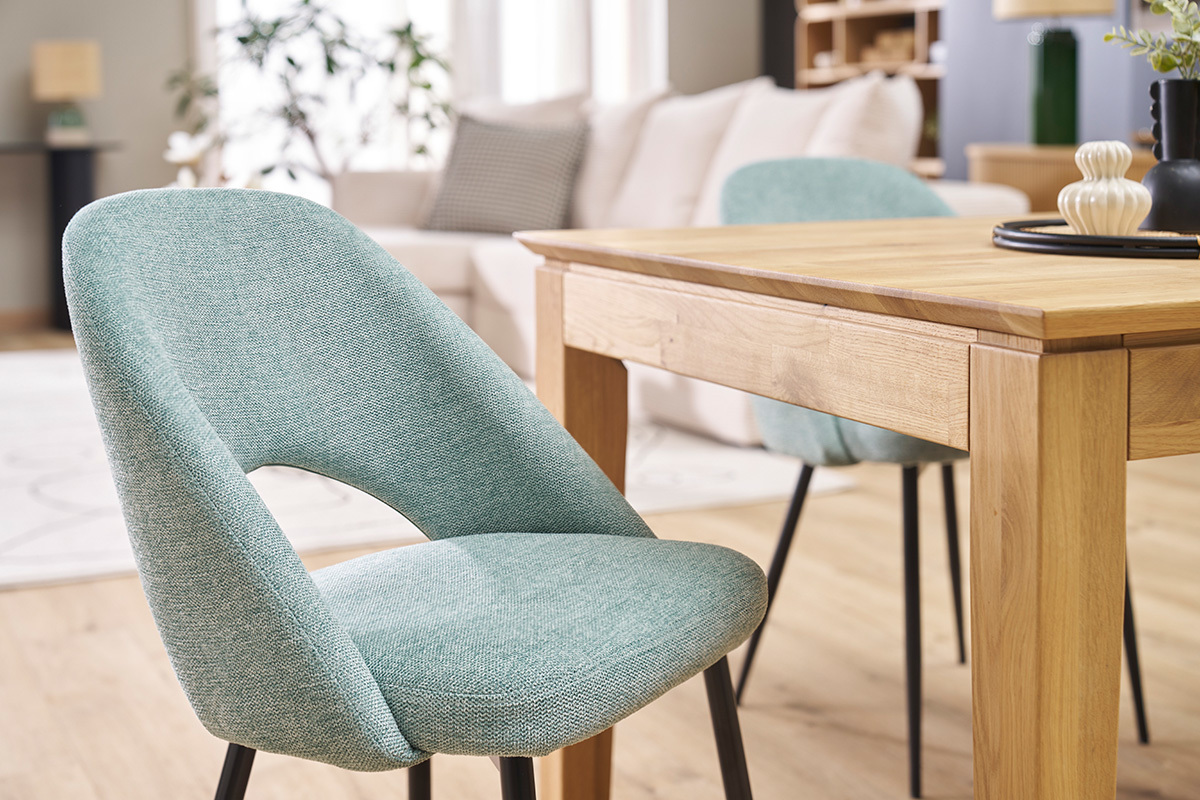 Chaises vintage vert cladon avec pieds noirs, prs d'une table en bois, dans un salon moderne.