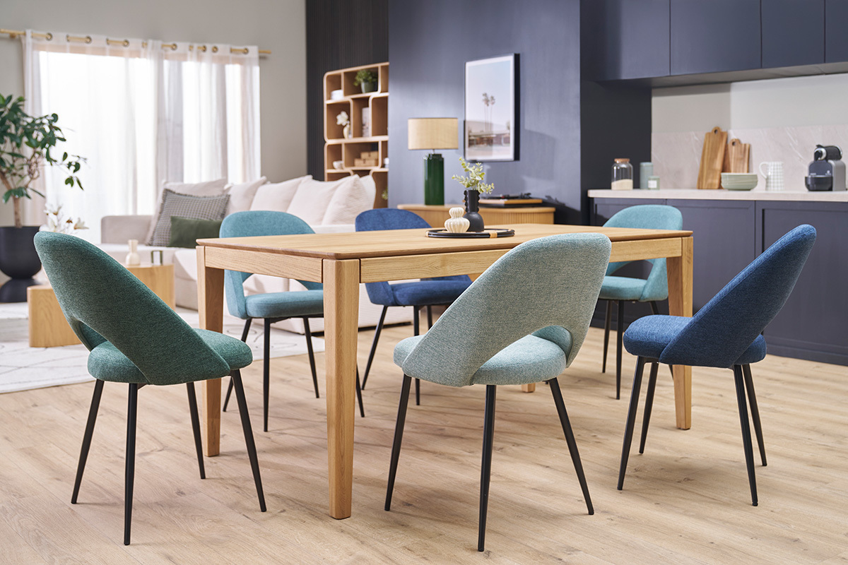 Chaises vert cladon en tissu velours et pieds mtalliques noirs autour d'une table en bois, vue intrieure.