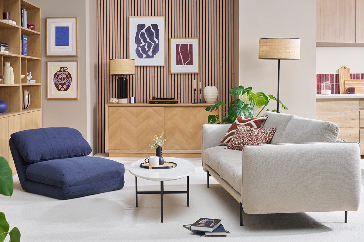 Chauffeuse convertible en velours ctel bleu fonc SPENCER dans un salon moderne avec canap et table basse.