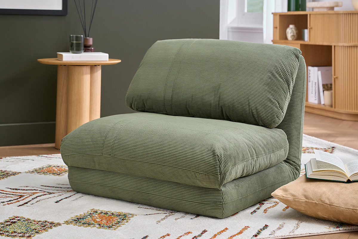 Chauffeuse convertible en velours c�tel� vert kaki, vue de 3/4dans un salon.