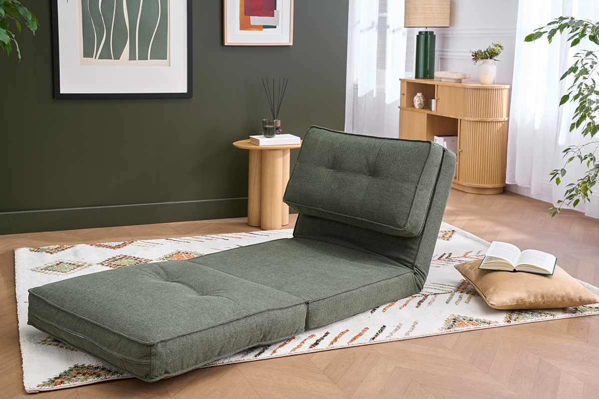 Chauffeuse convertible en tissu vert kaki, vue de c�t�, sur un tapis dans un salon lumineux.