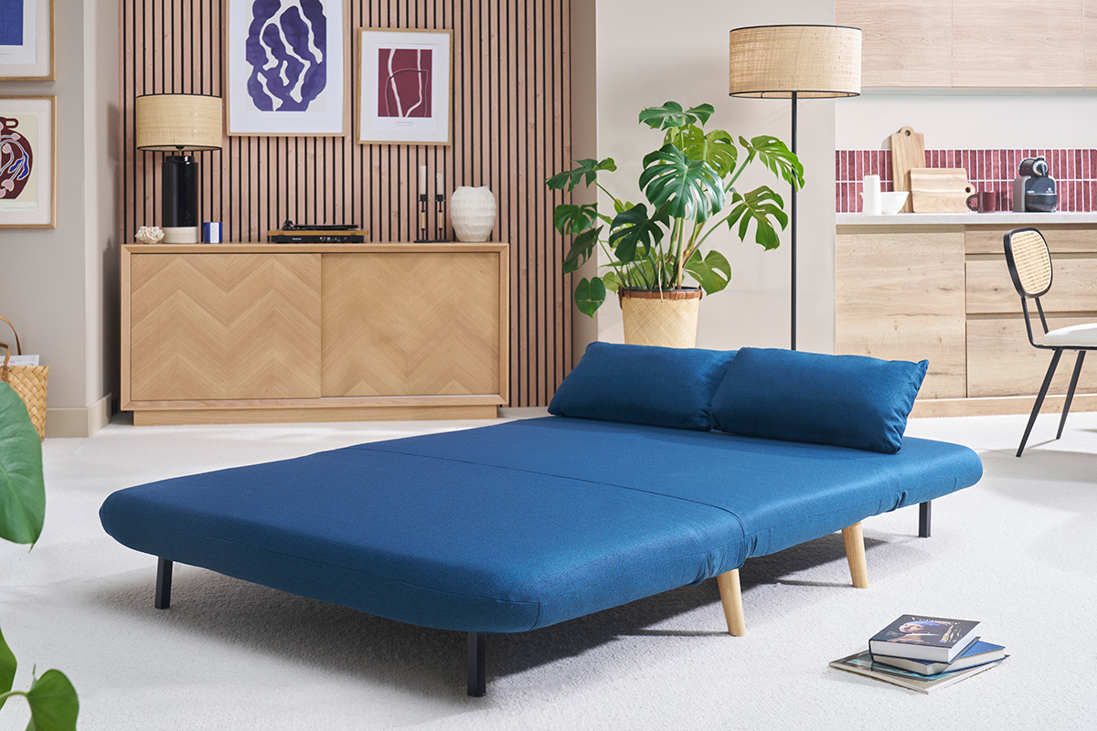 Chauffeuse AMIKO 2 places en tissu bleu fonc et bois clair, convertie en lit dans un salon moderne.