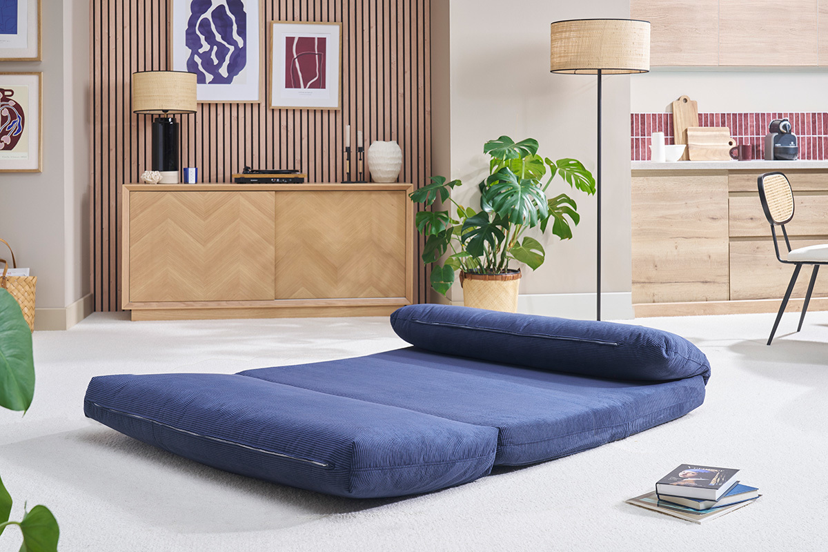 Chauffeuse convertible 2 places en velours bleu fonc dplie dans un salon moderne.