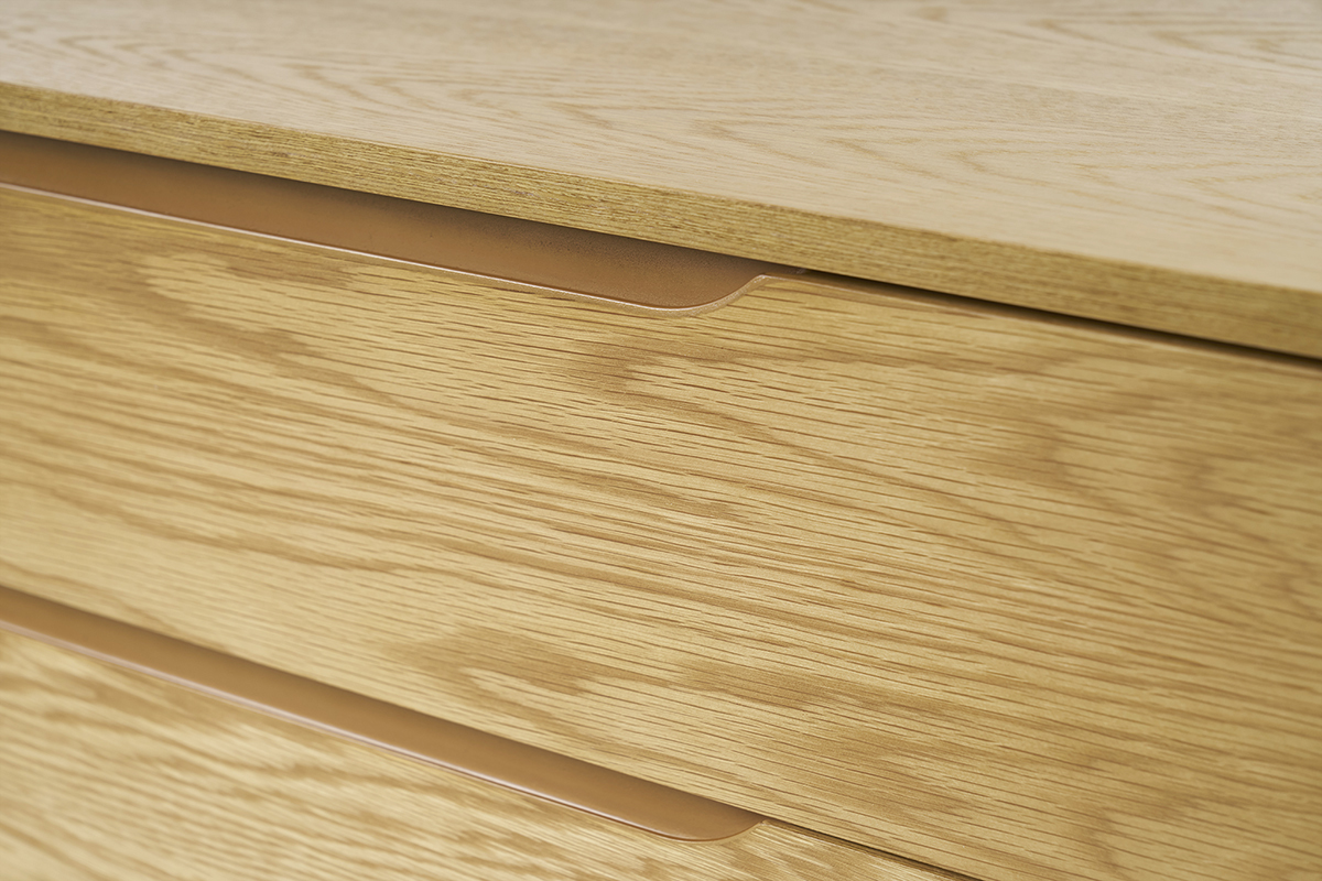 Gros plan de la commode scandinave en bois clair avec poignes intgres.