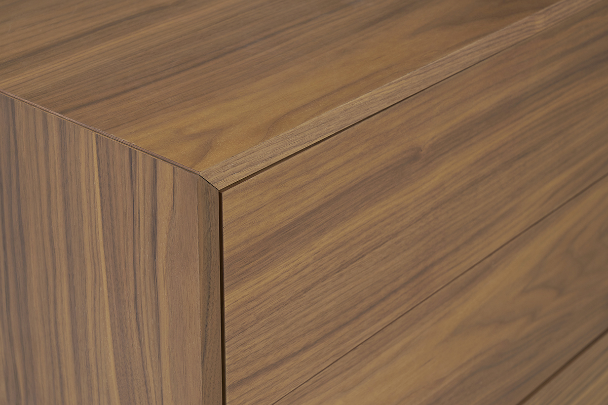 Vue de prs d'une commode en bois fonc noyer, montrant le grain du bois et les coins des tiroirs.