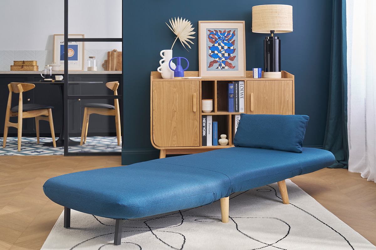 Fauteuil convertible bleu fonc AMIKO dpli dans un salon scandinave.