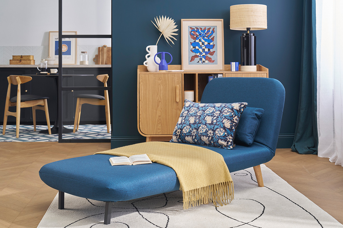 Fauteuil convertible AMIKO bleu fonc sur fond de dco scandinave, vue de profil.