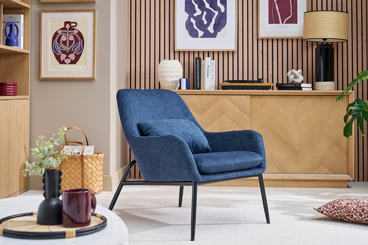Fauteuil bleu en tissu velours avec pieds en mtal noir dans un salon moderne.