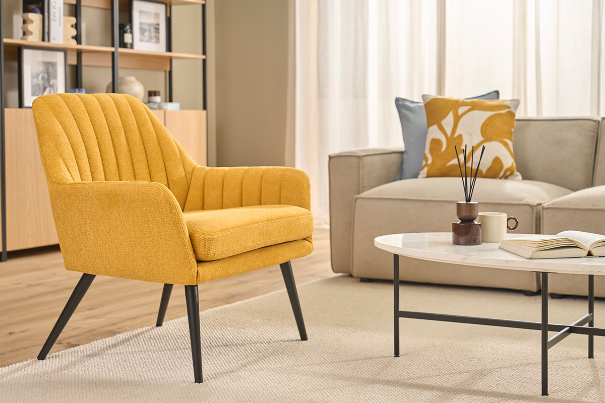 Fauteuil design jaune moutarde en tissu effet velours, vue de face, avec accoudoirs �vas�s et pieds en m�tal noir.