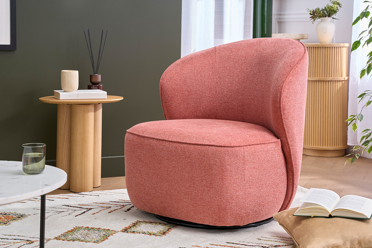 Fauteuil pivotant en tissu terracotta effet velours, vue d'angle, avec table d'appoint en bois.