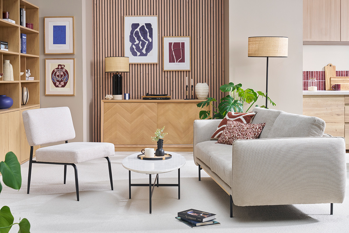 Fauteuil en tissu chenille beige et mtal noir, vue de ct dans un salon.