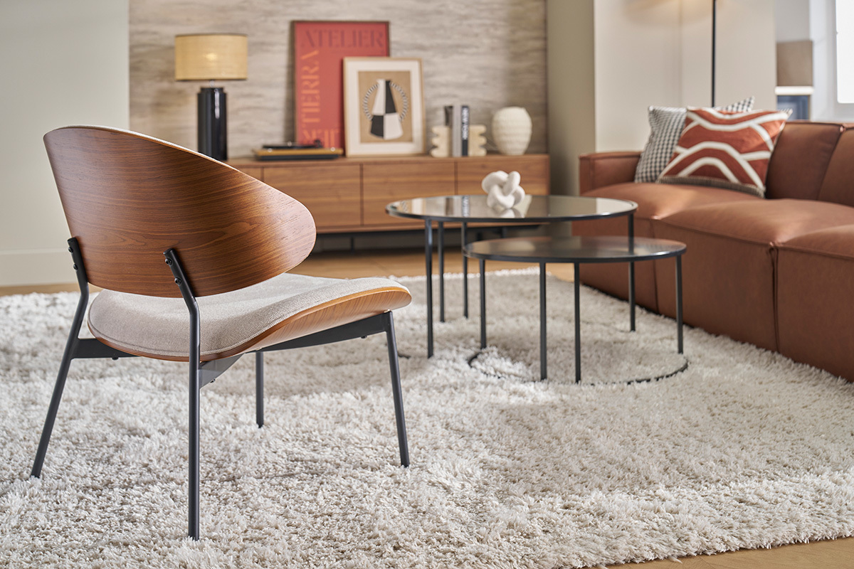 Fauteuil en tissu effet velours beige avec dossier en bois fonc, pos sur un tapis, vue arrire.