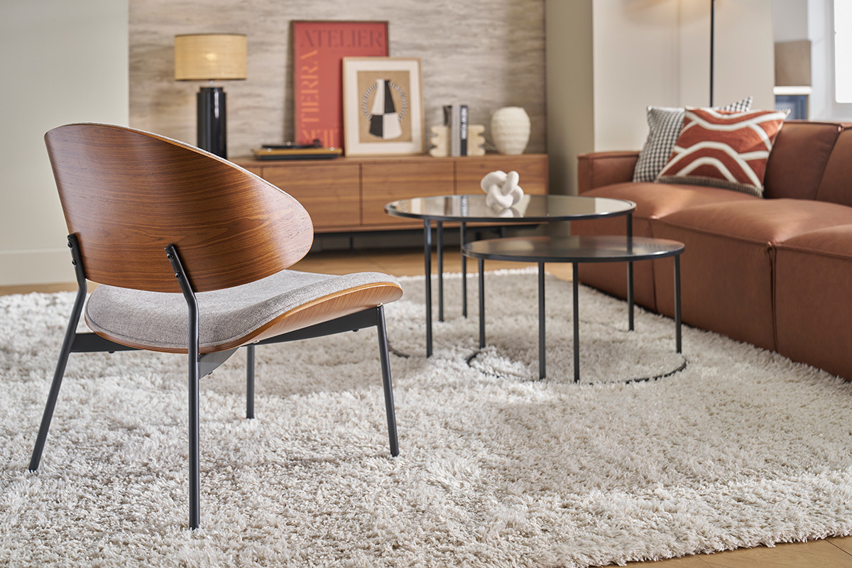 Fauteuil en tissu gris et bois fonc, vue de dos dans un salon moderne.