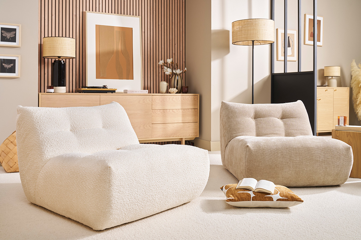 Deux fauteuils lounge dans un salon moderne, avec coussin et livre par terre.