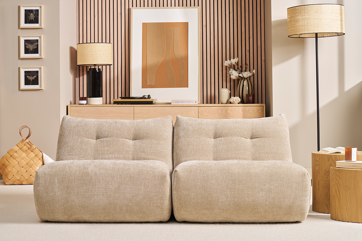 Salon avec deux fauteuils lounge BUMPY en velours taupe devant un meuble en bois.