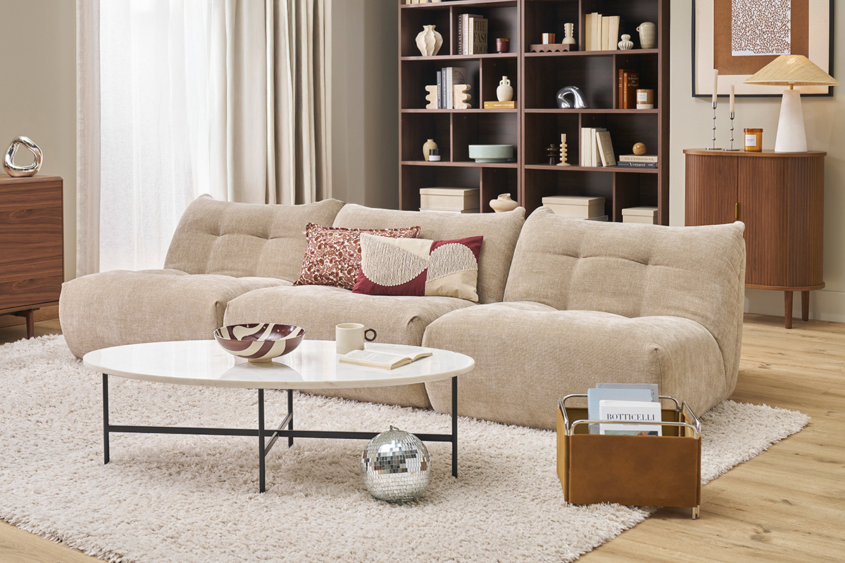 Fauteuil lounge en tissu velours taupe dans un salon lgant avec table basse blanche.