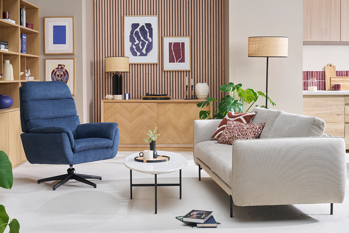 Fauteuil pivotant bleu JONAH dans un salon moderne avec canap beige et table ronde.