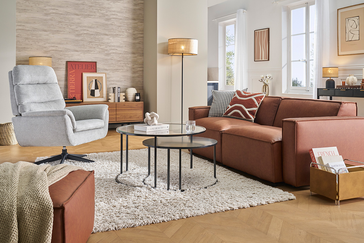 Fauteuil pivotant gris JONAH dans un salon moderne avec tables basses et canap marron.