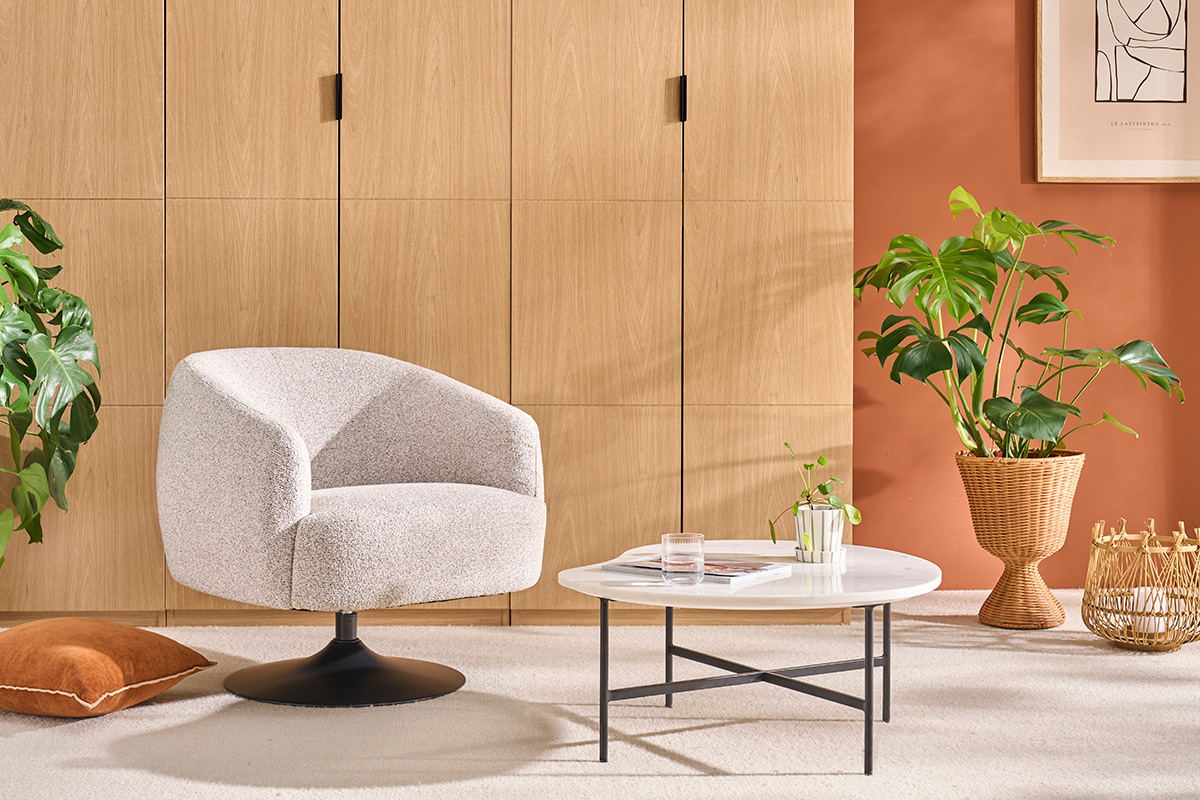 Fauteuil BOWIE en tissu effet chenille terre br�l�e, vue de 3/4avec table basse et plante.