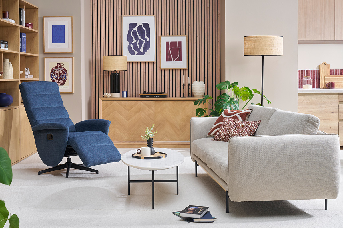 Salon avec fauteuil pivotant relax en tissu bleu et canap clair.