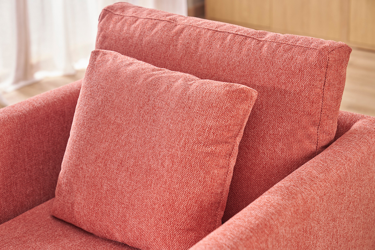Gros plan sur le dossier et le coussin du fauteuil scandinave terracotta en tissu effet velours.