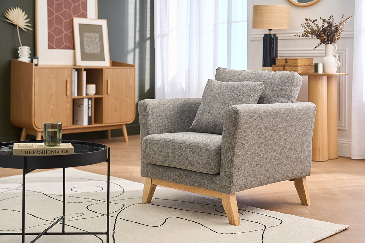 Fauteuil scandinave gris clair avec pieds en bois clair dans un salon moderne.