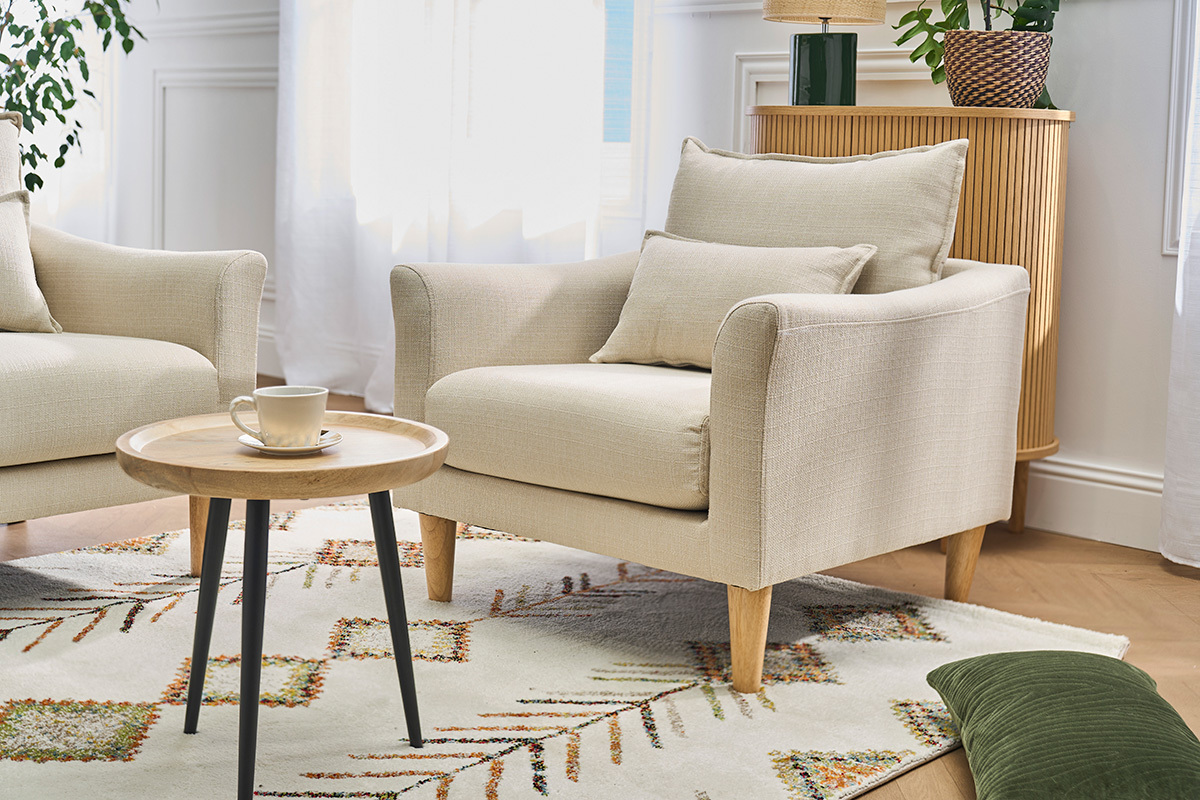 Fauteuil scandinave beige avec coussins, table basse, vue de trois-quarts.