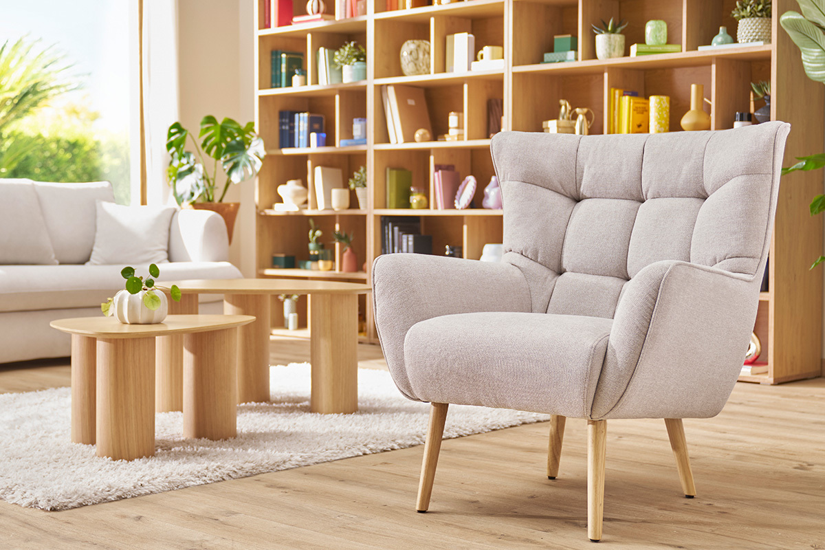 Fauteuil scandinave AVERY en tissu beige, pi�tement bois, dans un int�rieur lumineux.