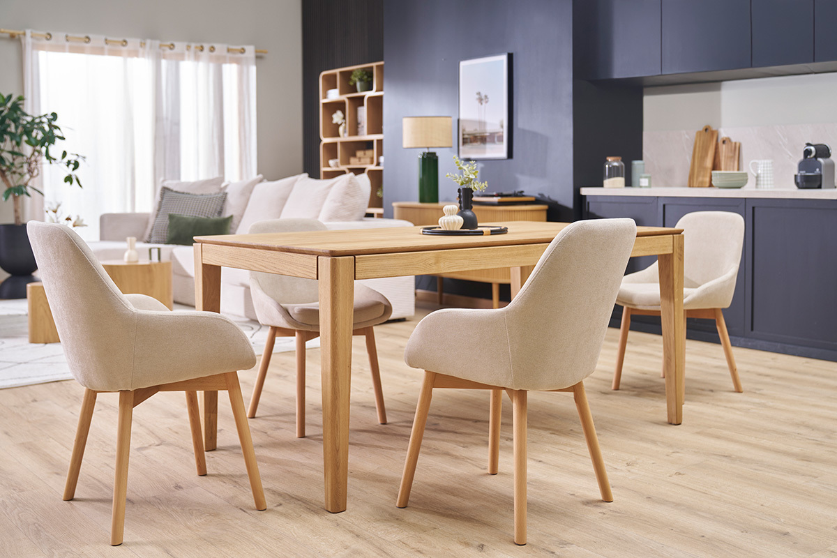 Fauteuils scandinaves en tissu beige et bois clair autour d'une table en bois.